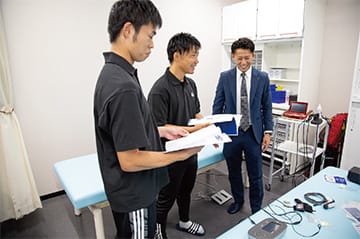 JFA 夢フィールド（海浜幕張）内のトレーナールームに設置された低周波治療器、超音波治療器、超短波治療器等と製品説明の様子